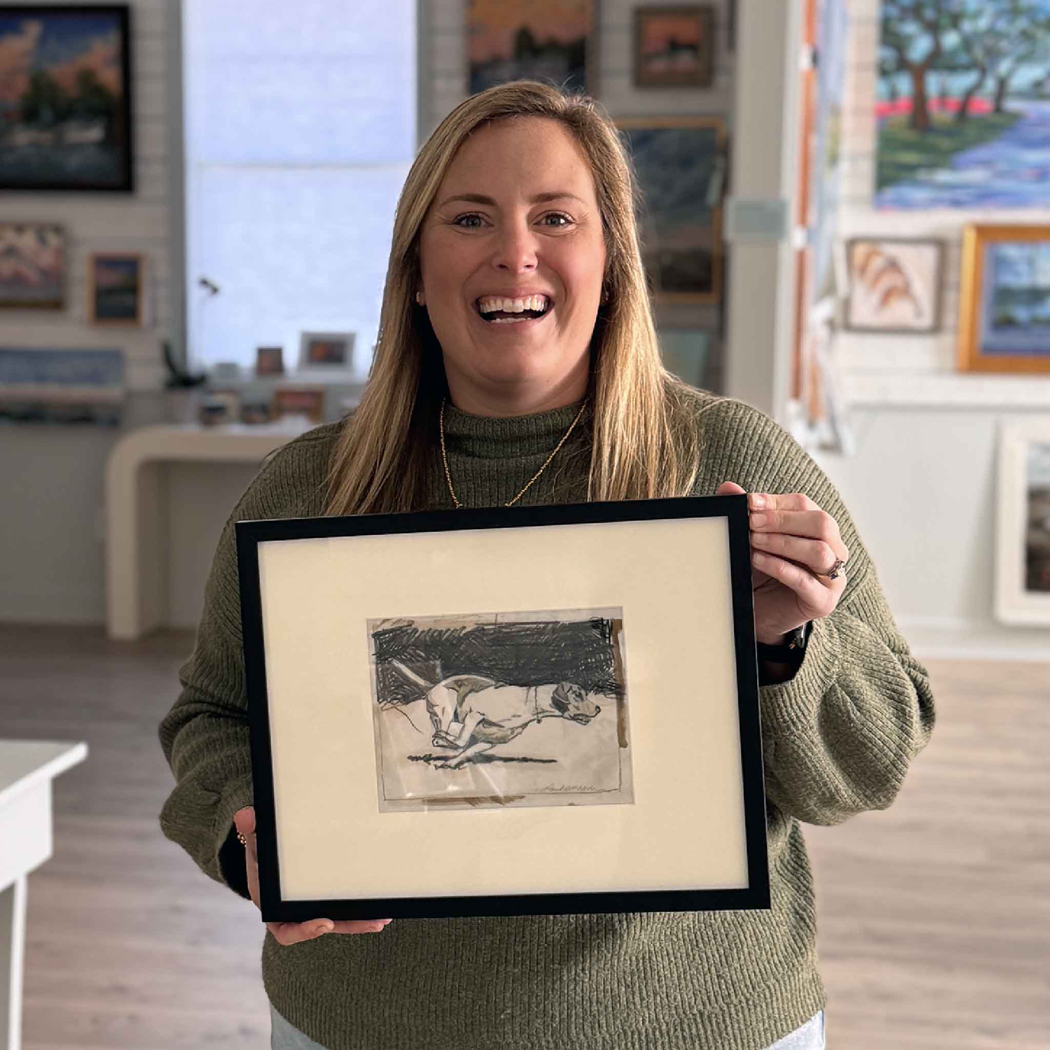 Gallery team member holding The Sprint by local artist Laurie McIntosh to show scale, a one-of-a-kind original monoprint capturing a dog in motion, photographed inside Gray Man Gallery.