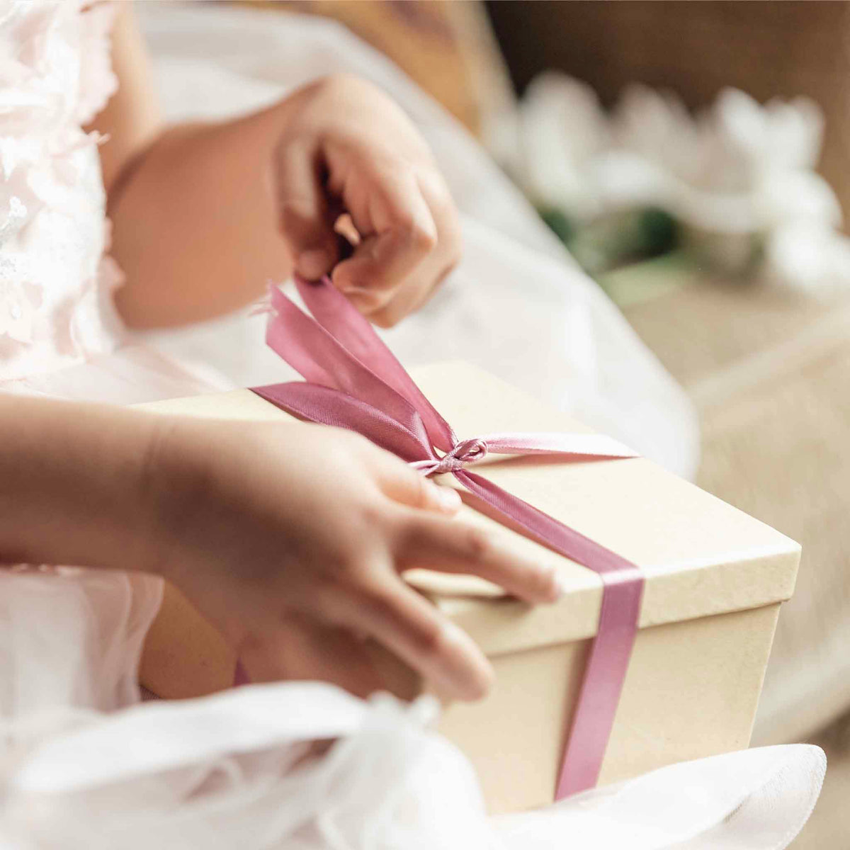 A thoughtfully wrapped gift box tied with a mauve ribbon, representing the Gifts Under $100 collection of art, pottery, books and distinctive finds from Gray Man Gallery in Pawleys Island, South Carolina.