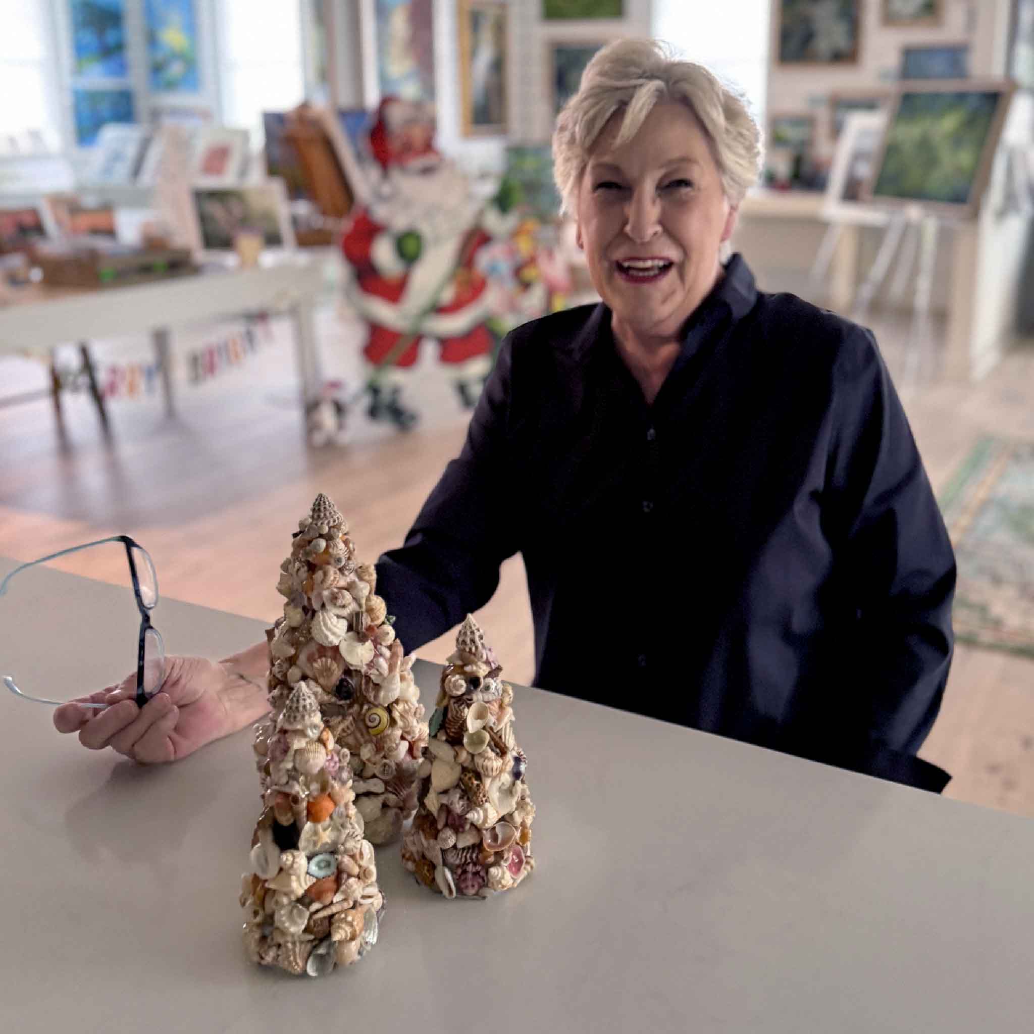 Three handcrafted shell trees by Tootsie Watkins displayed in the gallery, with Vida Miller.