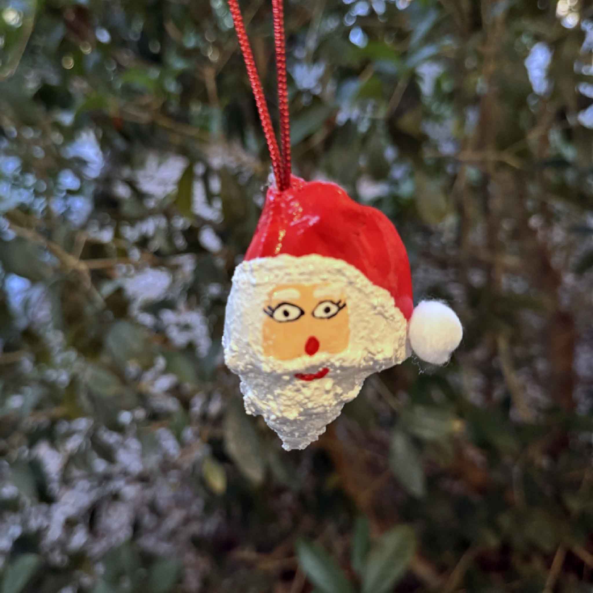 Hand-painted conch shell Santa ornament by Tootsie Watkins with red hat and textured white beard.