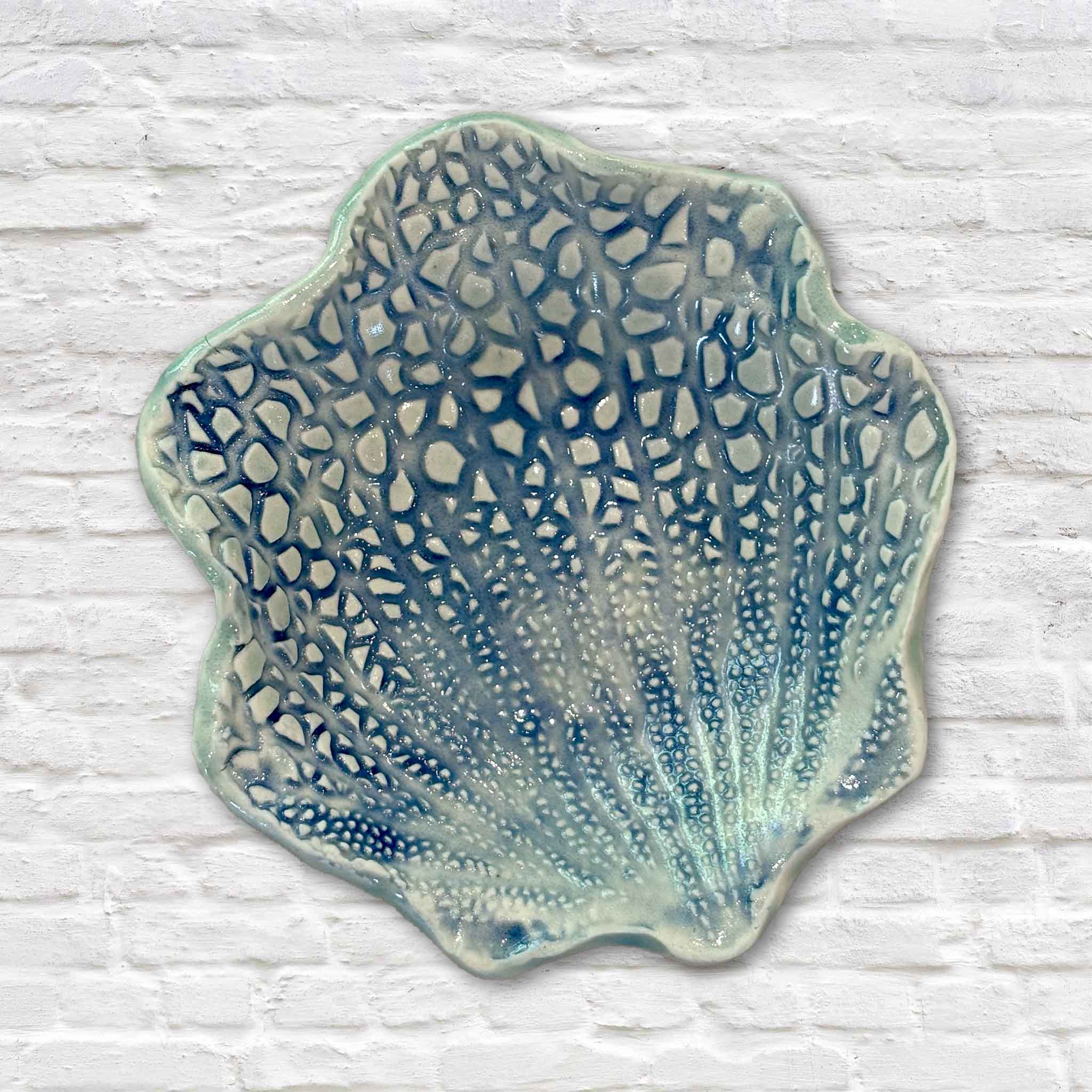 Handmade Coral Shell Dish by Lowcountry artist Vida Miller featuring an intricate openwork coral-inspired design finished in layered ocean-blue glazes. This one-of-a-kind piece of South Carolina coastal pottery is available at Gray Man Gallery in Pawleys Island and serves as both beautiful décor and a functional ceramic dish.