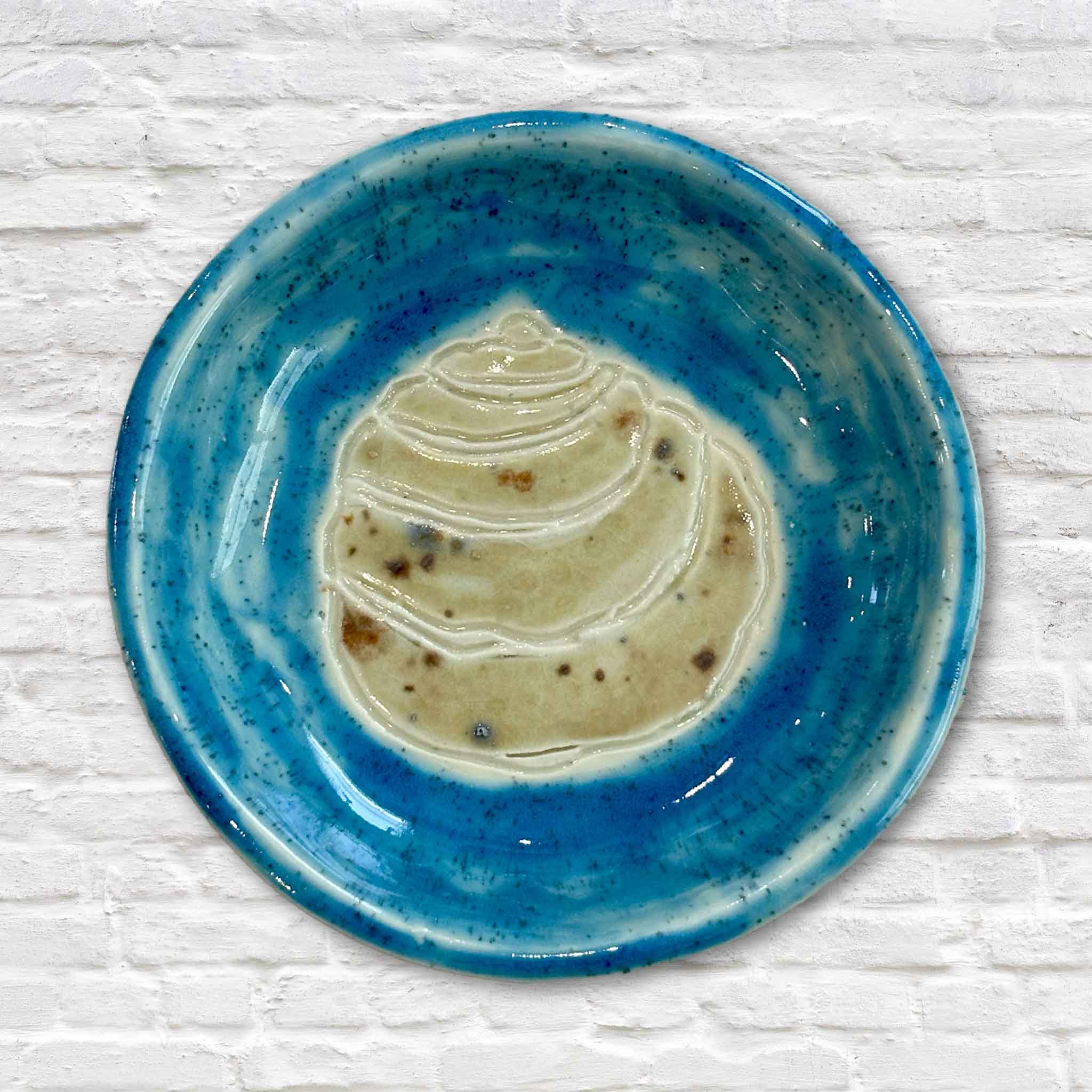 Handmade Pawleys Island Shell ceramic dish by Lowcountry artist Vida Miller featuring an embossed shell beneath a vibrant turquoise glaze. This one-of-a-kind piece of South Carolina coastal pottery is available at Gray Man Gallery in Pawleys Island and is perfect for holding jewelry, keys, sea glass, or other small treasures.