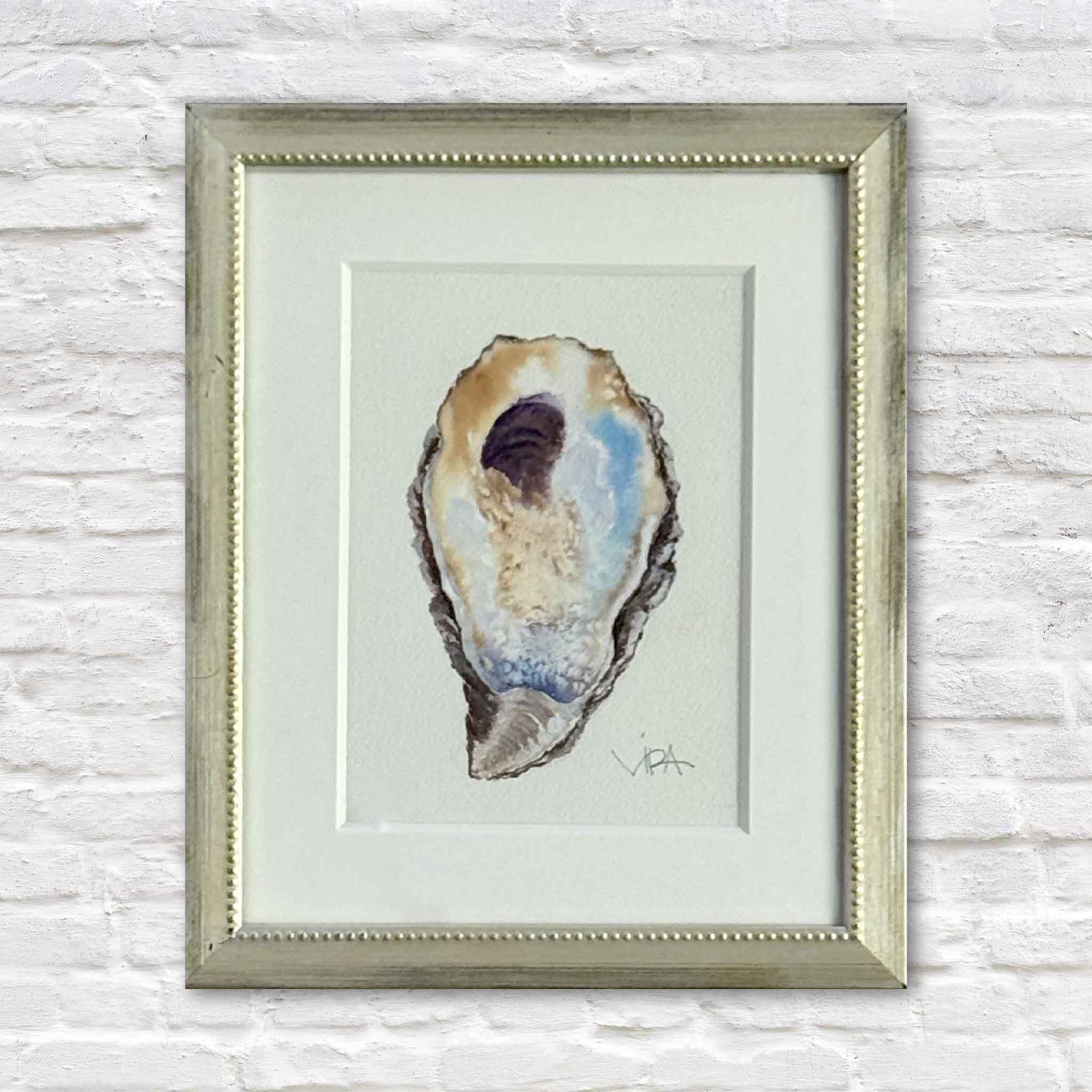 Gray Man Gallery team member holding Pawleys Oyster IV, an original watercolor painting by Pawleys Island artist Vida Miller, beautifully matted and framed in a softly antiqued metallic beaded frame inside Gray Man Gallery in Pawleys Island, South Carolina.