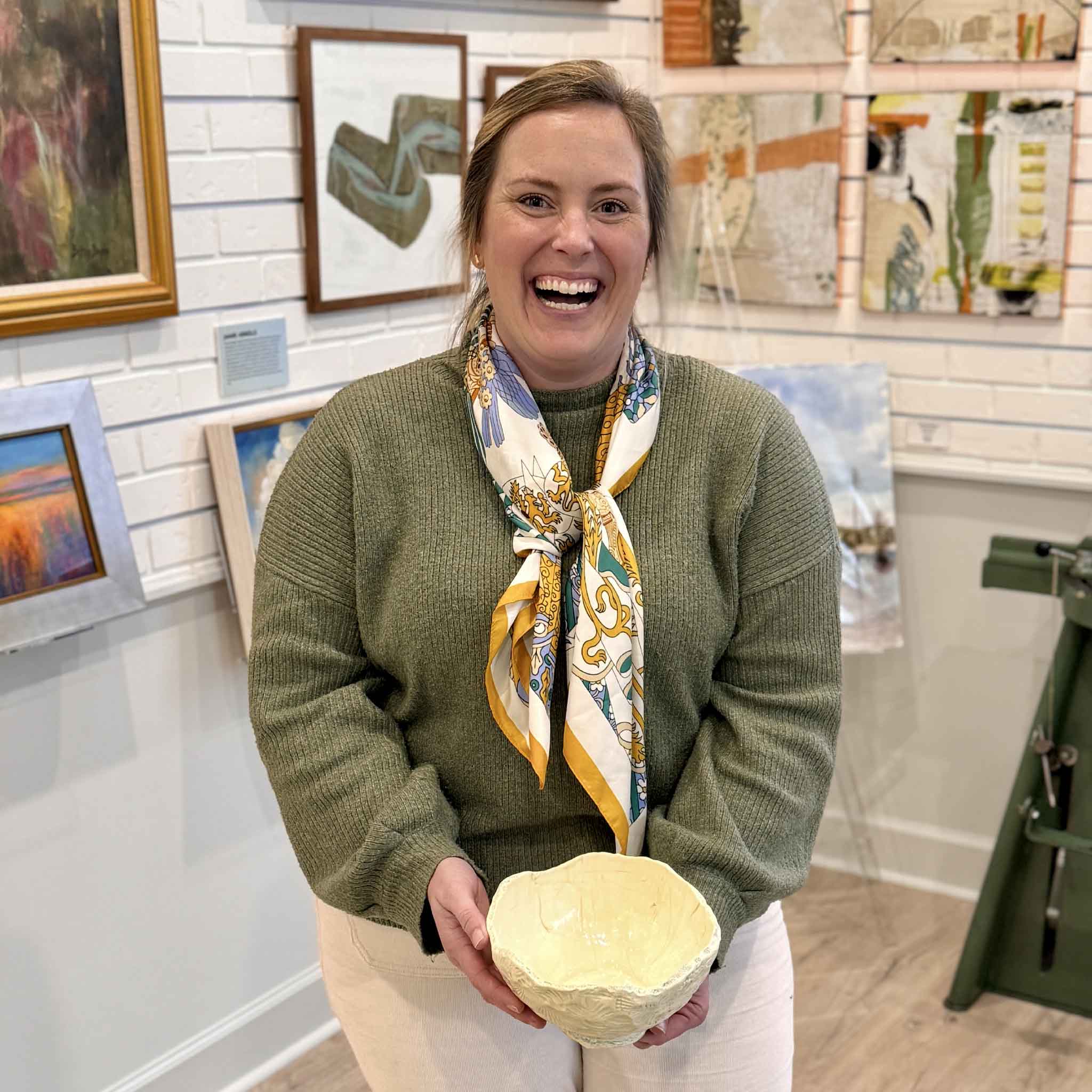 Bordy holding founding artist of Gray Man Gallery Vida Miller's handmade Pawleys Shore Shell Bowl inside the Pawleys Island art gallery, showcasing local ceramic craftsmanship