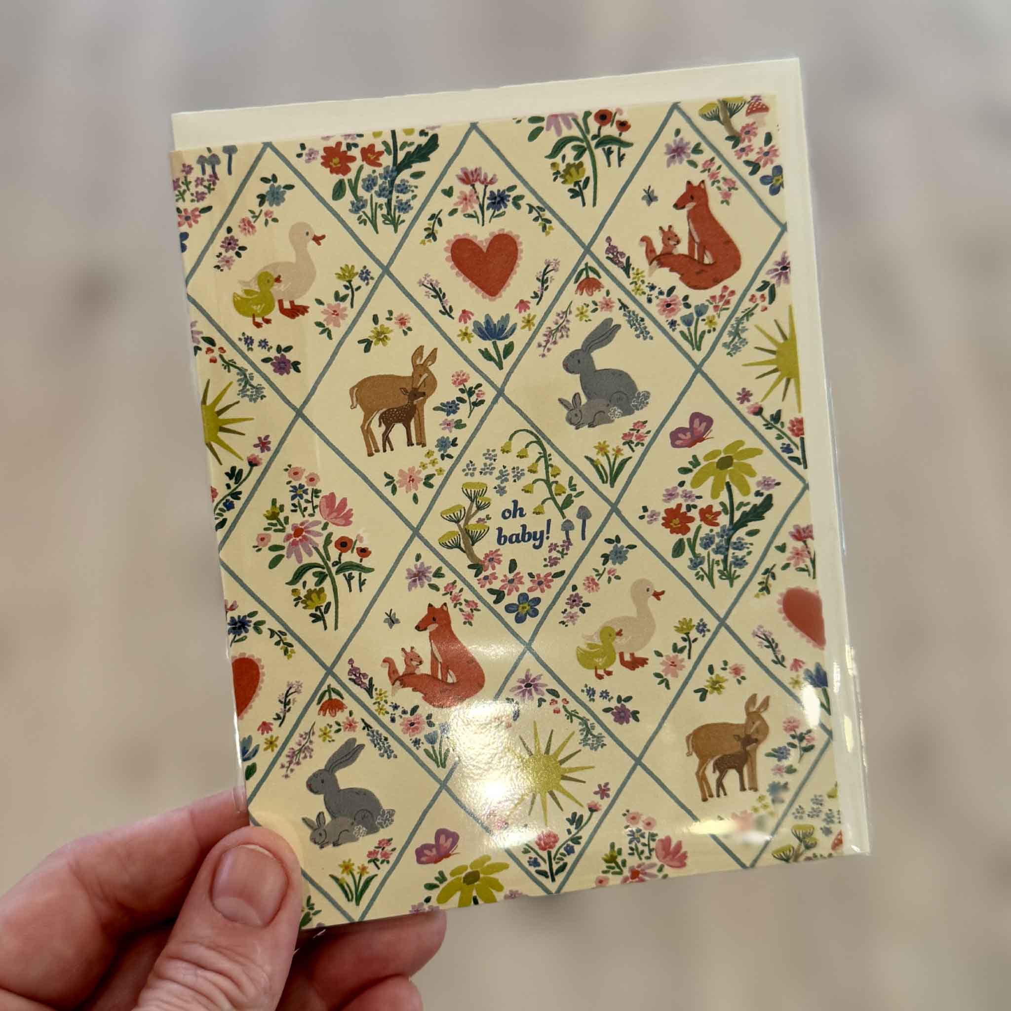 Woodland Critters baby greeting card illustrated by The House That Lars Built for Red Cap Cards featuring woodland animals, colorful flowers, hearts, and butterflies surrounding a sweet "oh baby!" message. Available at Gray Man Gallery in Pawleys Island, South Carolina.
